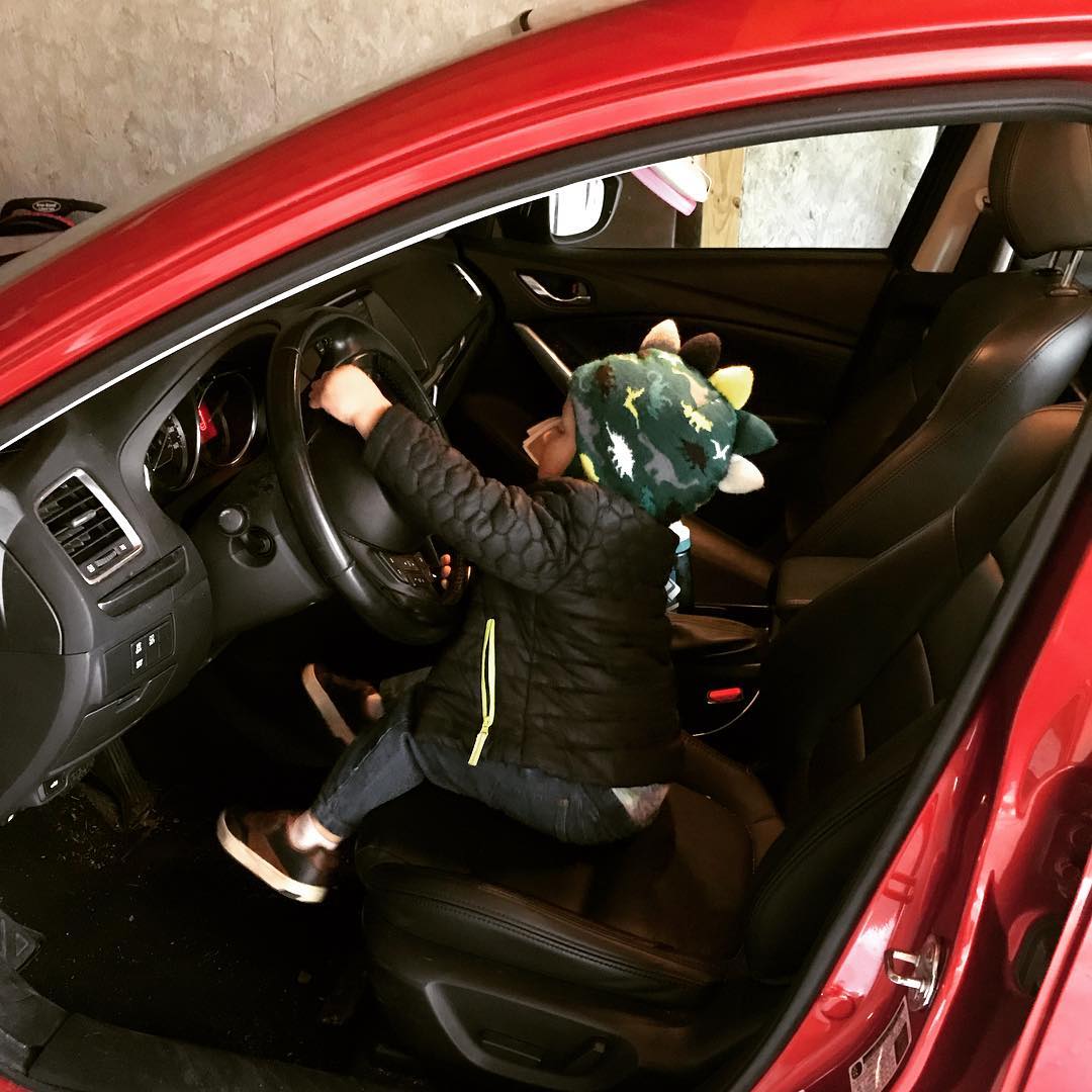 Two year old pretending to drive a car.